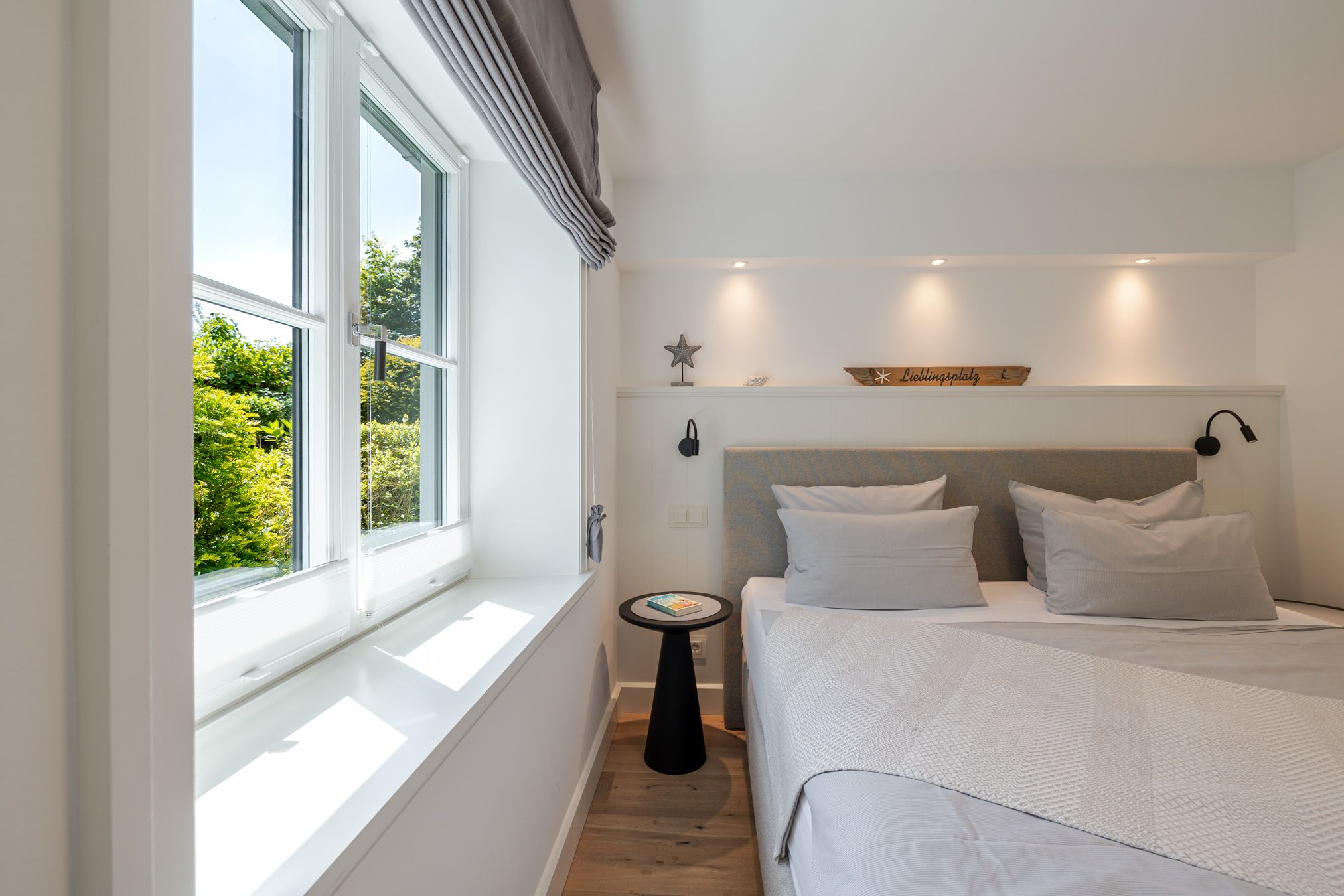 Schlafzimmer mit Doppelbett und Fenster ins Grüne